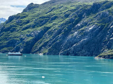 A boat on the water with a mountain in the background. The scene captures a serene and picturesque landscape with the boat floating on the body of water and a mountain towering in the distance.