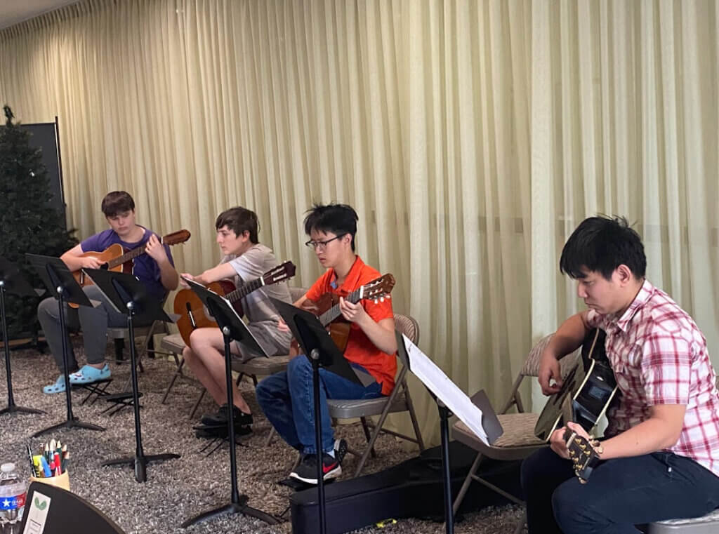 Guitar Group Class. There are 4 boys holding guitars their hands.